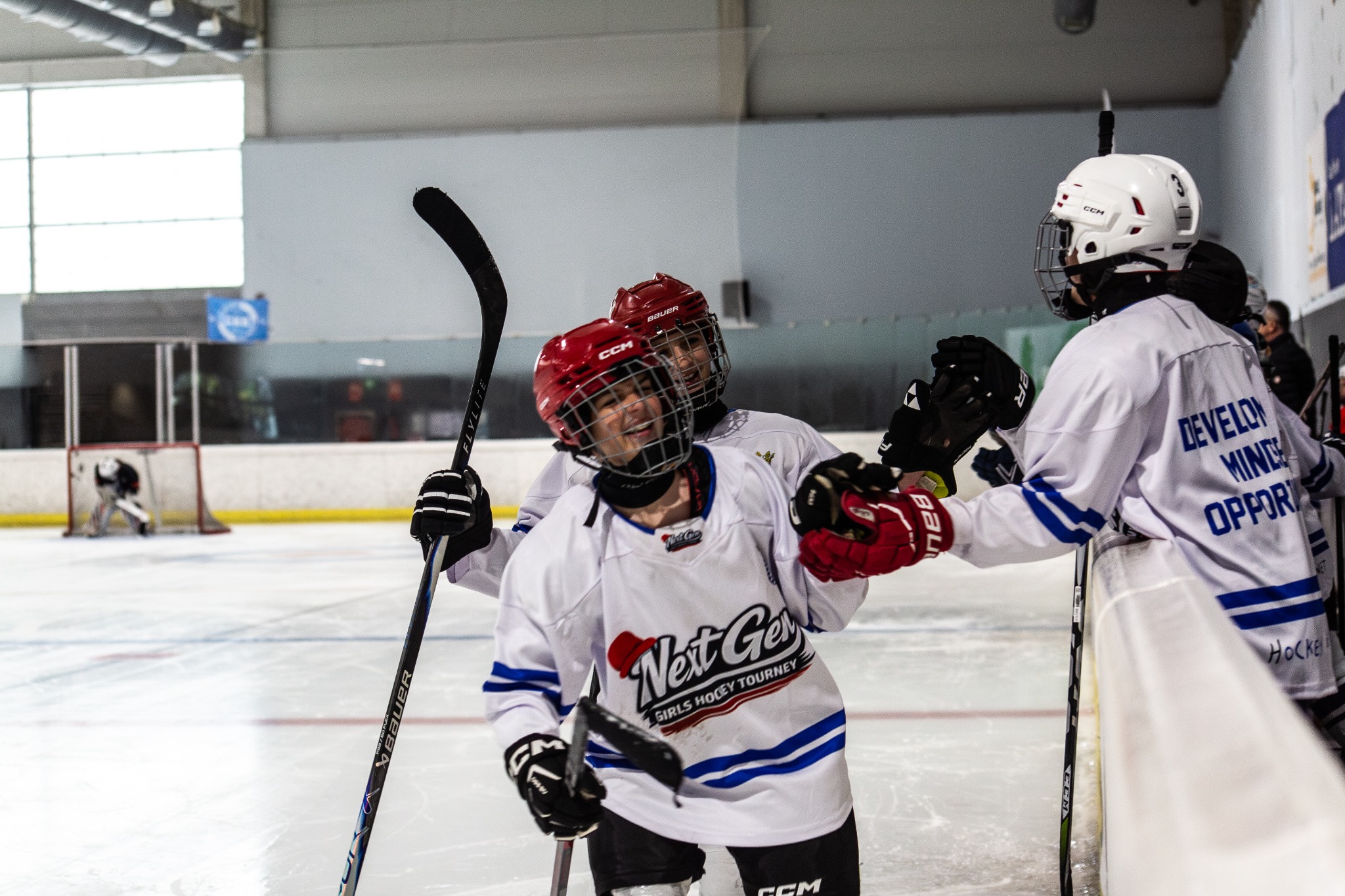 Next Gen hockey players in white jerseys celebrating together on the ice